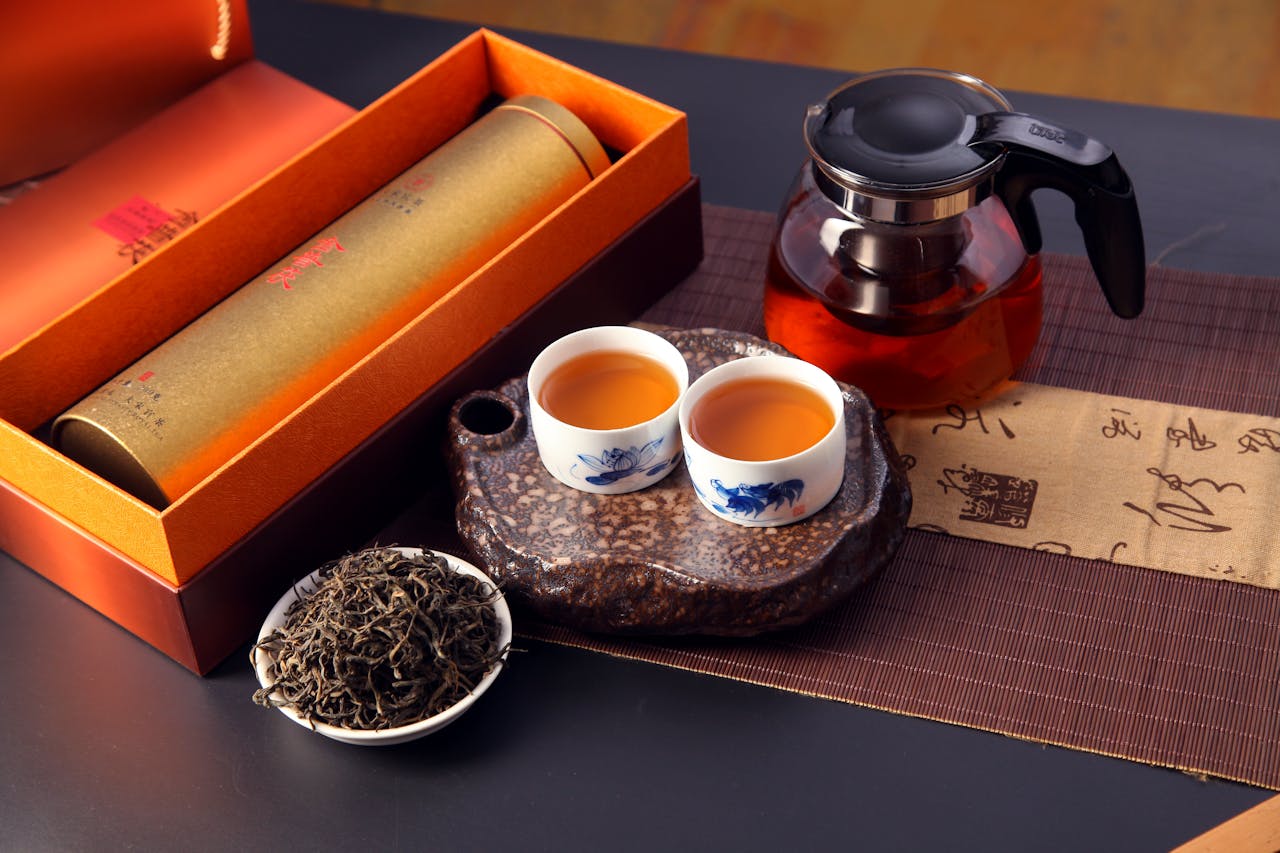 A beautifully arranged Chinese tea ceremony featuring teapot, cups, loose leaves, and an elegant gift box.