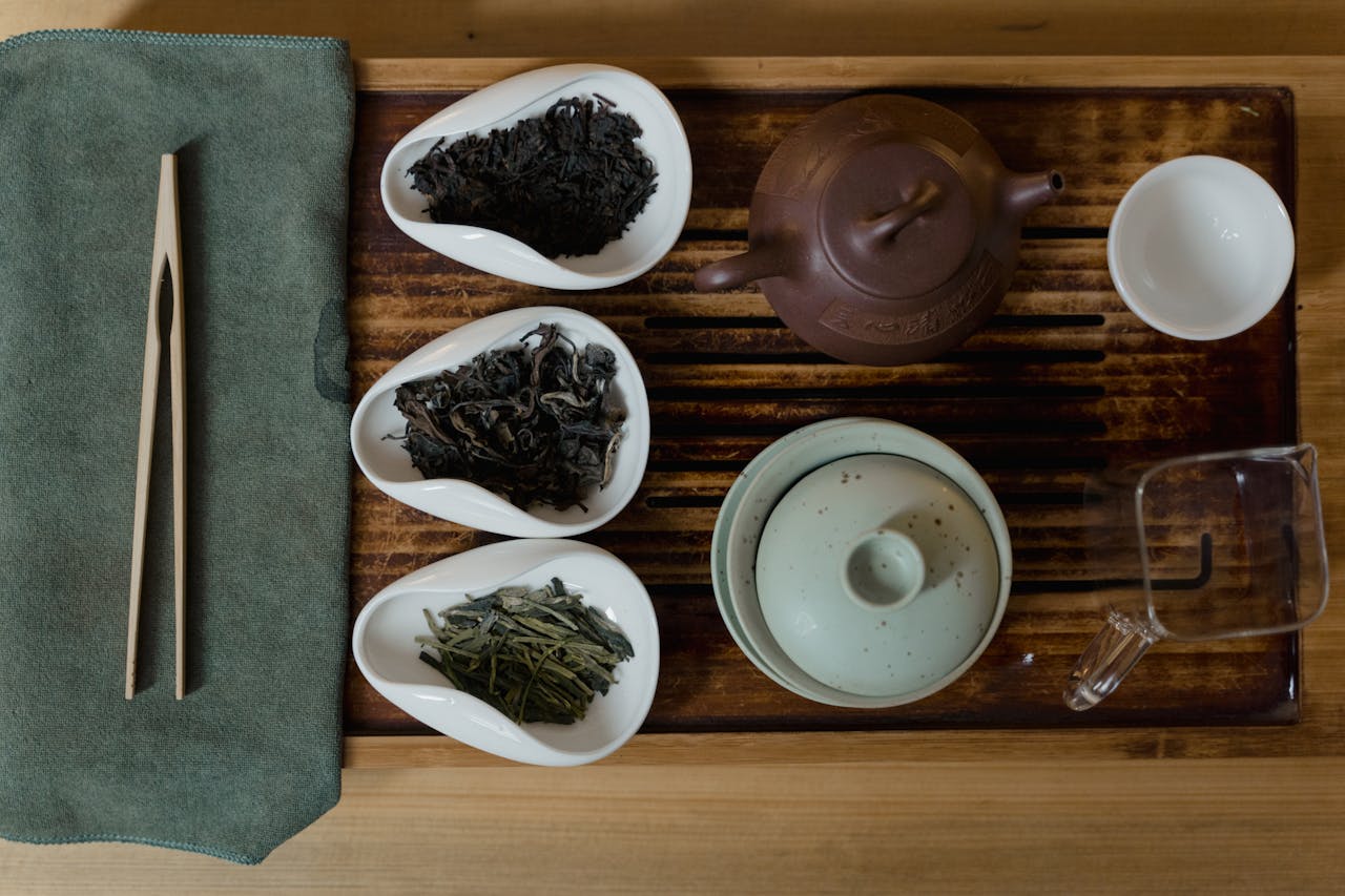 Artistic setup of a traditional Asian tea ceremony with cups, teapots, and tea leaves.