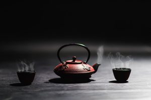 Minimalist image of a cast iron teapot and steaming cups, perfect for traditional tea culture themes.